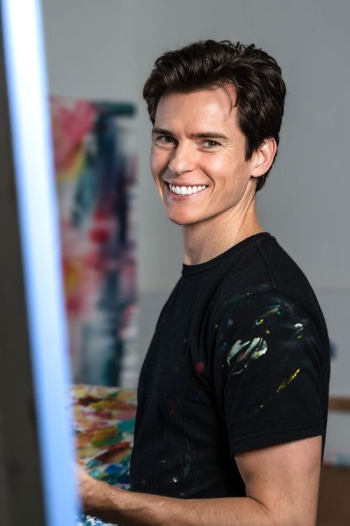 Portrait of artist Kyle Lucks smiling in his studio